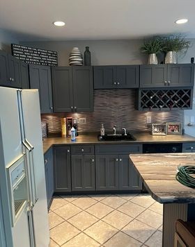 Modern kitchen with gray cabinets, countertop decor, and a refrigerator next to an island bar.